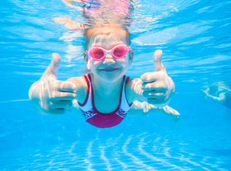 girl swimming underwater giving two thumbs up